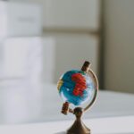 Close-up of a miniature globe on a wooden desk in an interior setting.